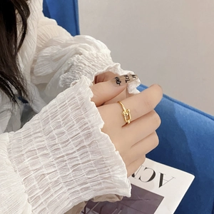 Close-up of a gold U-shaped link ring worn on a finger with minimalist fashion styling