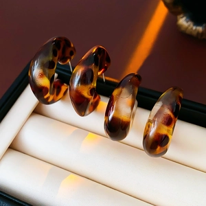 Detailed view of four leopard print resin C-shaped earrings on a premium jewelry cushion