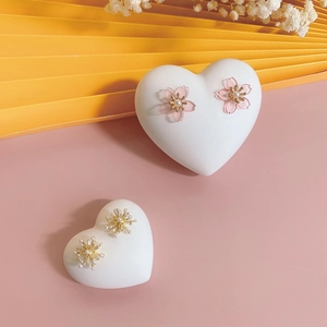 Detail showing pink cherry blossom and golden sunflower studs on a decorative stand