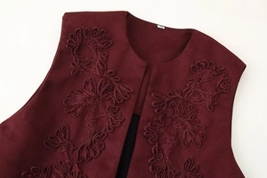 Detailed close-up of dark red suede vest featuring delicate floral embroidery on collar