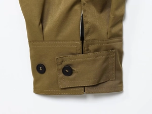 Close-up of khaki pleated jacket cuff with black buttons and fine stitching details