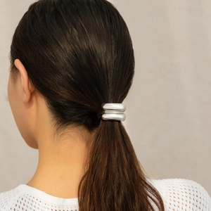 Detail of a minimalist matte silver double-ring hair tie worn on a ponytail