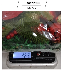 Detail view of a 463g Christmas wreath with red berries and ornaments on a digital scale