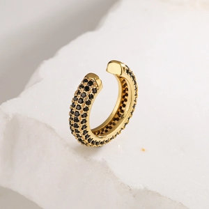 Luxurious gold U-shaped ear cuff with black zircon stones on a textured stone surface