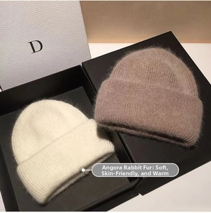 Detail view of angora rabbit hair knit beanies in cream and light brown gift boxes