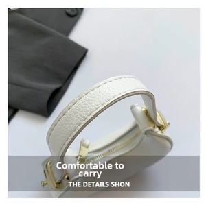 Macro shot of white lychee leather texture and golden metal buckle on the crescent bag