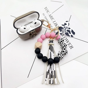 Detail of cow print beads and Mama charm keychain on a brown earphone case