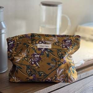 Caramel jacquard toiletry bag with vintage pattern on a wooden table in home setting