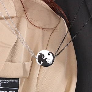 Gros plan de colliers chat yin yang noir et blanc portés par un couple élégant