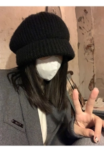 Close-up of black knit beret worn by a model in a gray suit for a soft indoor look