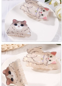 Detail of two cute cat-shaped hair claws with pearlescent finish on a white plate