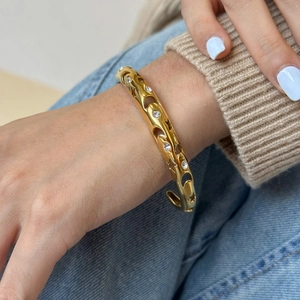 Detailed view of a gold-plated open cuff bracelet with hollow patterns and sparkling zircons