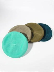 Detail of knitted berets in mint green, khaki, olive green, and navy blue with rich texture