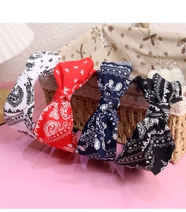 Detailed paisley print bow headbands in white red navy and black on a woven basket