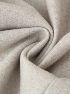 Détail macro du tissu en laine mélangée crème montrant une texture douce et épaisse