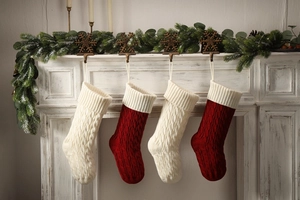 Close-up of red and beige cable knit Christmas stockings hanging on a white fireplace mantle