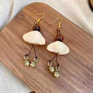 Macro view of vintage style wood bead and gold acorn earrings on a walnut display board