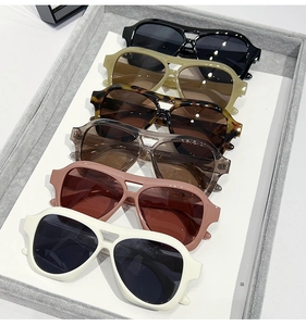 Flat lay of wide double-bridge pilot sunglasses in various frame colors on display tray