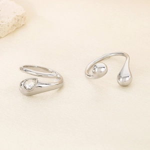 Detail of silver teardrop rings with one clear gemstone and one smooth metal finish