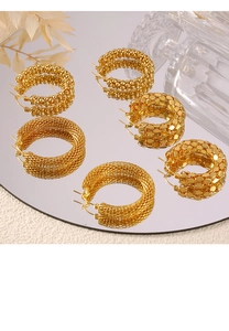 Dettaglio di tre orecchini a forma di U placcati in oro con diverse trame su uno specchio