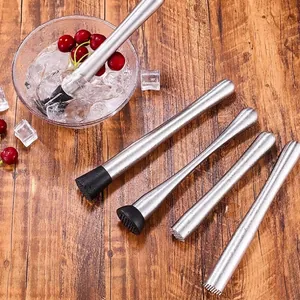 Set of five stainless steel cocktail muddlers with textured heads on a wooden background