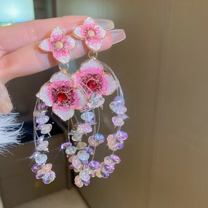 Macro detail of pink flower earrings with sparkling tassels and crystal accents