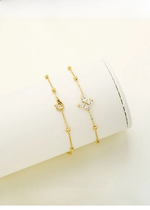 Detail of gold titanium steel bracelets with clover and vortex charms set with cubic zirconia