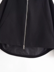 Detail shot of silver metal zipper and curved hem on black wool coat for women