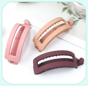 Dettaglio di fermagli a banana opachi in rosa, beige e rosso scuro con design traforato