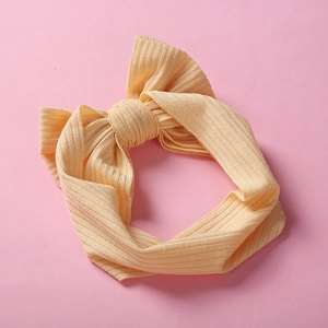 Fascia per neonati in maglia giallo chiaro con grande fiocco su sfondo rosa