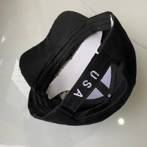 Detail of adjustable back strap on black cotton cap with white USA embroidery