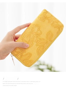 Close-up of bright yellow long wallet featuring embossed rose floral texture and gold zipper