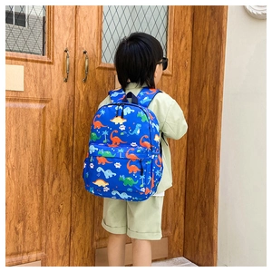 Blue kids dinosaur backpack worn by a child featuring colorful cartoon prints and pockets