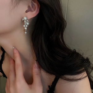 Macro shot of elegant silver-colored tassel earrings with pearls and rhinestones on a model