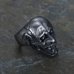 Macro shot of an antique silver skull mask ring on a dark rock background