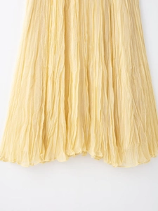 Close-up of yellow pleated maxi skirt showing delicate wrinkled chiffon fabric texture