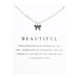 Macro shot of a silver bow pendant necklace on a white display card with inspirational text