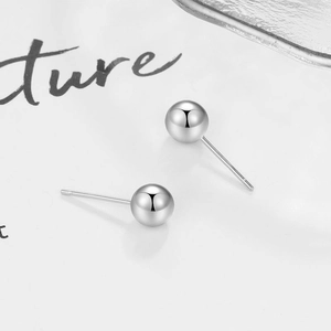 Macro detail of high-polished S925 sterling silver ball stud earrings on white background