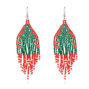 Macro detail of handmade bohemian beaded tassel earrings with Christmas tree pattern