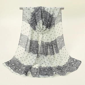 Vue détaillée d'une écharpe en mousseline blanche avec pois noirs et broderie florale en dentelle