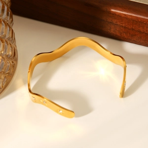 Détail du bracelet ondulé en acier plaqué or 18 carats avec pierres serties en étoile