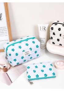 Detailed shot of quilted floral makeup bags with cute flower-shaped zipper and woven label