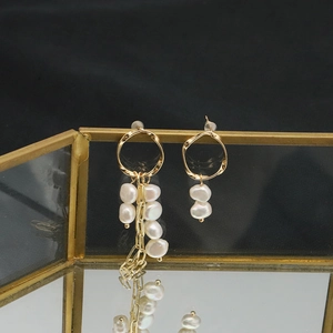 Elegant asymmetric gold long fringe earrings with baroque freshwater pearls on display