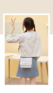 Close-up of white crossbody bag with pink floral embroidery and clear base detail