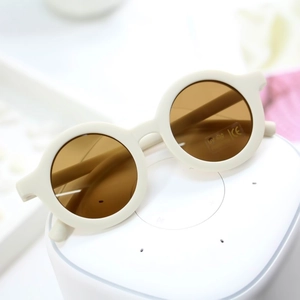 Close-up of matte beige round kids sunglasses showing UV400 protection and CE mark