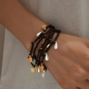 Détail macro du bracelet multicouche en cordon noir avec breloques goutte or et argent