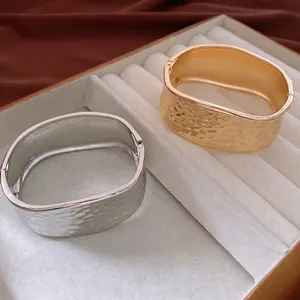 Textured gold and silver cuff bracelets with hammered finish in a white velvet jewelry box