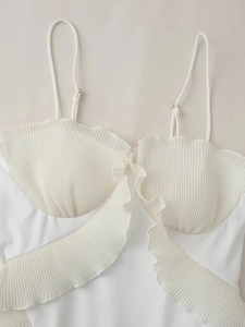 Détail de robe plissée blanche montrant la texture coquille et les fines bretelles