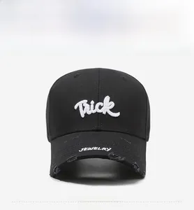 Close-up of black cotton baseball cap with white Trick embroidery and distressed brim details