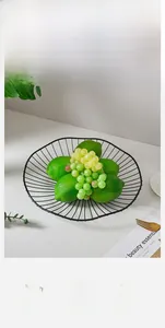 Close-up of a black geometric wire fruit bowl holding fresh lemons and grapes in a modern home